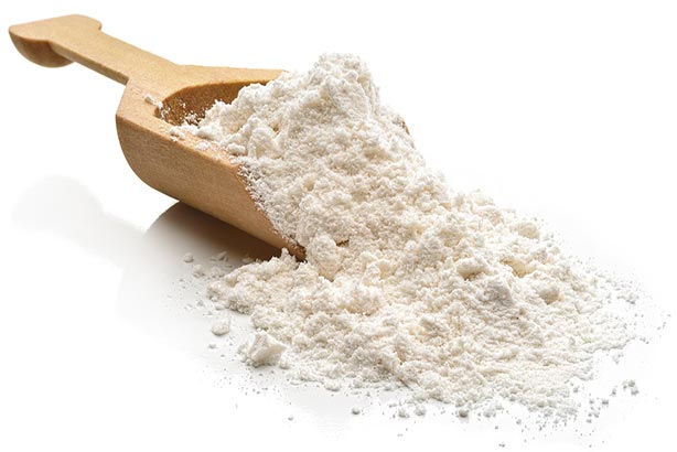A scoop of dairy ingredients in a wooden spoon
